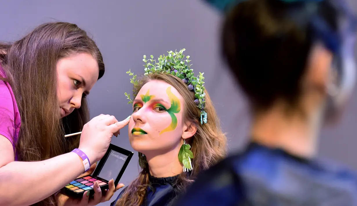 Seorang makeup artist merias model saat mengikuti kompetisi makeup di International "Crystal Angel" Festival of Hairdressing ke-15 di Kiev (22/4). (AFP/Sergei Supinsky)