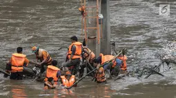 Sejumlah pasukan oranye berjibaku membersihkan sampah batang kayu dan bambu yang tersangkut di aliran sungai Ciliwung di kawasan Sudirman, Jakarta, Jumat (9/2). (Liputan6.com/Faizal Fanani)