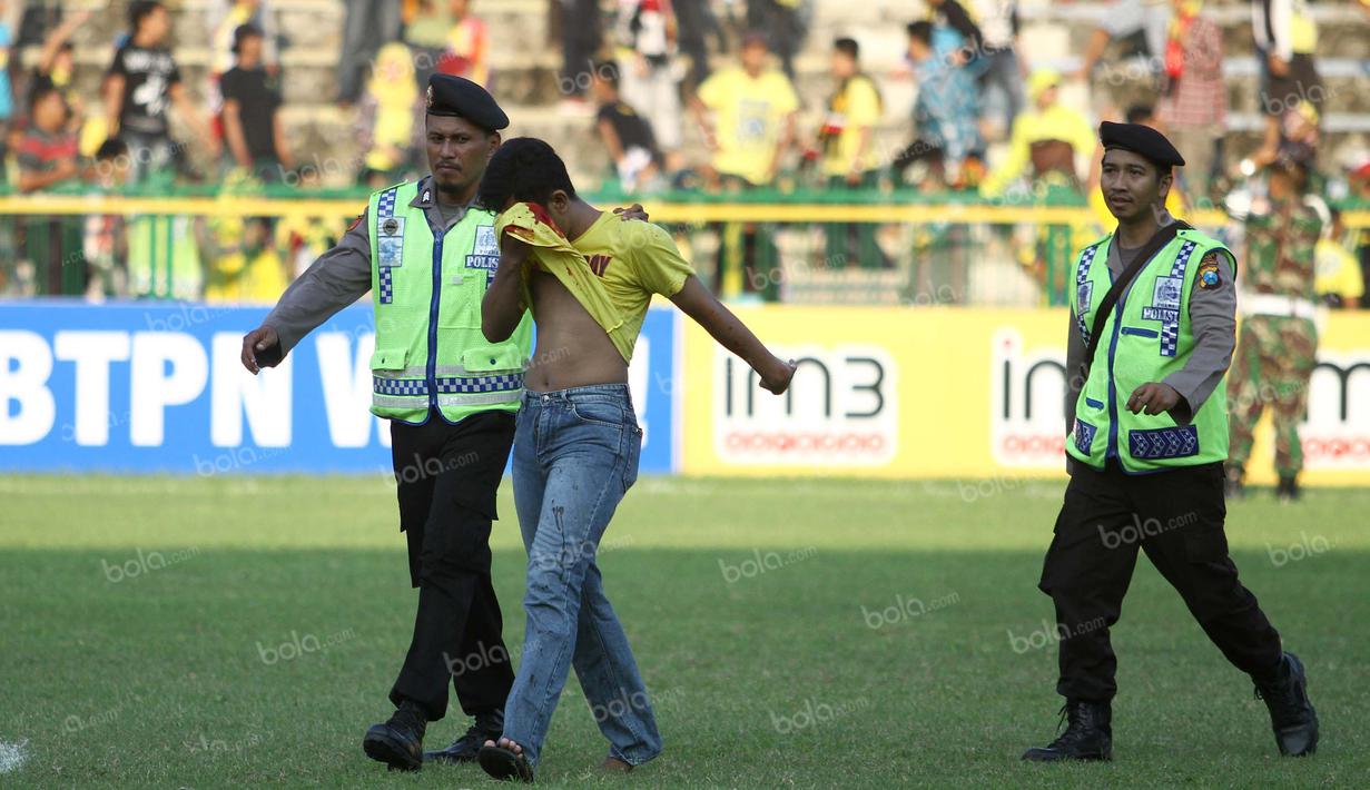 Polisi membantu suporter yang terluka saat terjadi keributan antar suporter dalam laga Gresik United melawan PS TNI di Stadion Tri Dharma, Gresik, Minggu (22/5/2016). (Bola.com/Fahrizal Arnas)