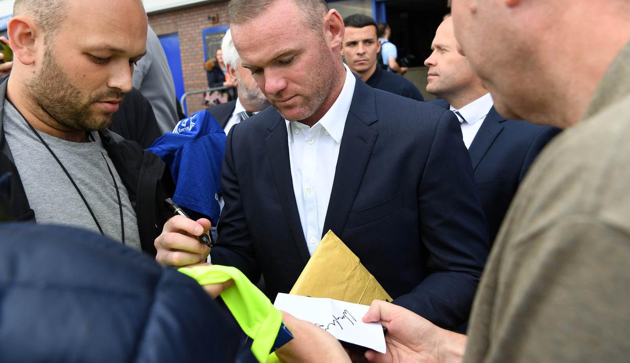 Pemain anyar Everton, Wayne Rooney, memberikan tanda tangan kepada para fans yang menghadiri jumpa pers perkenalan dirinya di Goodison Park, Liverpool, Senin (10/7/2017). (AFP/Paul Ellis)