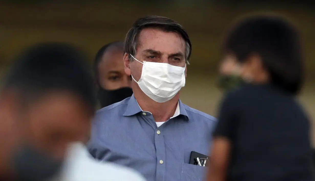 Presiden Brasil Jair Bolsonaro mengenakan masker saat menemui para pendukungnya di luar Istana Alvorada, Brasilia, Brasil, Jumat (24/7/2020). Jair Bolsonaro dinyatakan positif terinfeksi COVID-19 pada 7 Juli lalu. (AP Photo/Eraldo Peres)