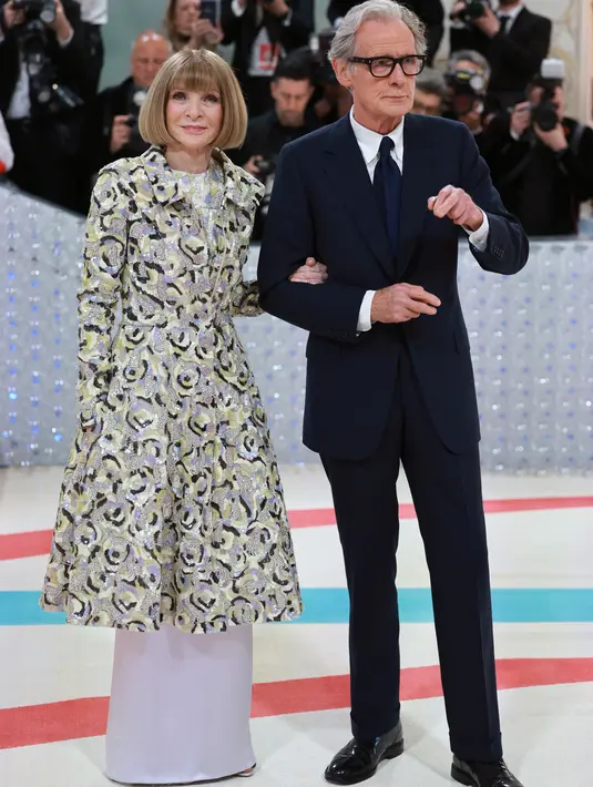 Tersenyum di hadapan para paparazzi, Anna Wintour memamerkan penampilan Manolo Blahnik kustomnya, sementara Nighy berjas hitam tradisional. (Photo by Theo Wargo / GETTY IMAGES NORTH AMERICA / Getty Images via AFP)