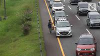 Pedagang menawarkan daganganya ke para pemudik di Jalan tol Cikopo - Palimanan KM 73, Purwakarta, Jawa Barat, Sabtu (30/4/2022). Padatnya arus lalu lintas ruas tol trans jawa, membuat pedagang asongan turun ke jalan. (Liputan6.com/Herman Zakharia)