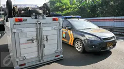 Mobil polisi berada disamping mobil boks yang terbalik di KM 02 Tol Cawang arah Cililitan, Jakarta, Senin (30/5). Belum diketahui apa penyebab kecelakaan termasuk ada tidaknya korban akibat kecelakaan itu. (Liputan6.com/Yoppy Renato)