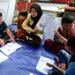 Guru mengajari murid-murid korban gempa belajar di dalam tenda darurat yang dibangun di halaman sekolah di SDN Gintung, Mangunkerta, Cianjur, Jumat (23/12/2022). Lebih dari sebulan sejak musibah gempa bumi 5,2 SR sejumlah murid sekolah di Cianjur masih belajar pada tenda darurat. (merdeka.com/Arie Basuki)