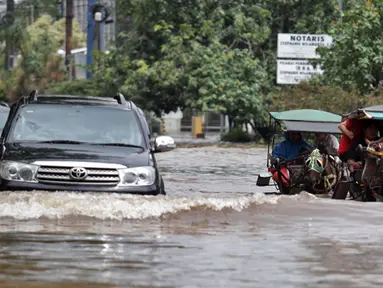 Hujan yang mengguyur Jakarta sejak Minggu (8/2) lalu, mengakibatkan tingginya genangan air di kawasan Kelapa Gading. Tampak mobil dan delman berusaha menerobos banjir, Jakarta, Selasa (10/2/2015). (Liputan6.com/Faizal Fanani)