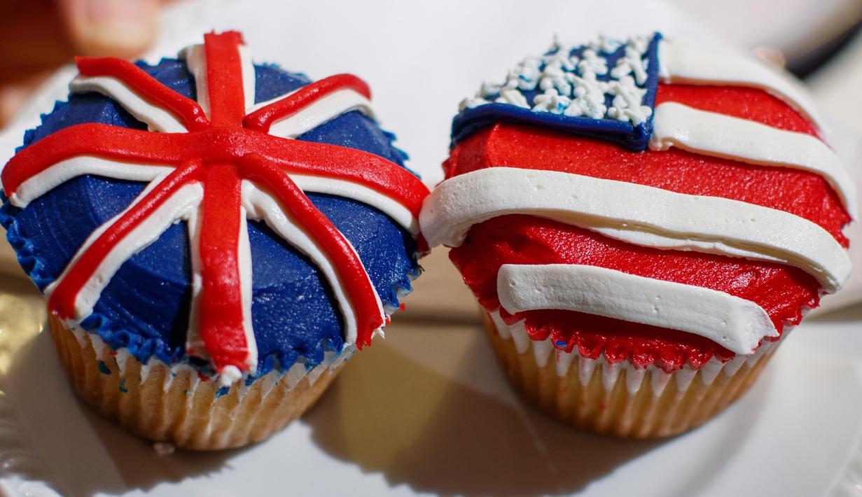 Karyawan memperlihatkan cupcakes edisi khusus untuk menghormati pernikahan Pangeran Harry dan Meghan Markle di Hummingbird Bakery, London, 11 Mei 2018. Pernikahan Harry dan Meghan digelar 19 Mei esok di Kapel St. George, Istana Windsor. (AFP/Tolga AKMEN)