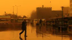 Sejumlah orang berjalan saat badai pasir menerjang Kota Diyarbakir di Turki, Jumat (19/1). Hempasan badai pasir tampak membuat pemandangan di Turki menjadi kuning kemerah-merahan. (AFP PHOTO / Ilyas AKENGIN)