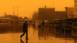 Sejumlah orang berjalan saat badai pasir menerjang Kota Diyarbakir di Turki, Jumat (19/1). Hempasan badai pasir tampak membuat pemandangan di Turki menjadi kuning kemerah-merahan. (AFP PHOTO / Ilyas AKENGIN)