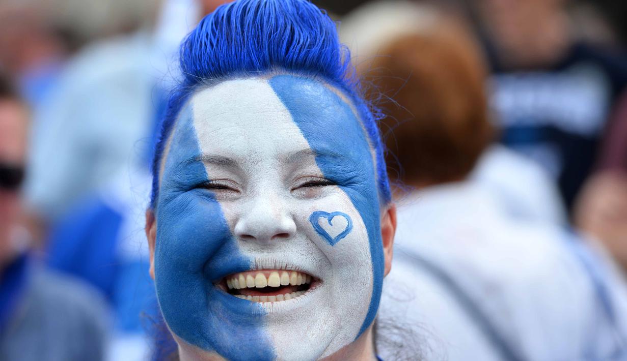 Seorang suporter menghias wajahnya dengan warna kebanggan Leicester City saat merayakan titel juara Liga Inggris di Stadion King Power, (7/5/2016). (AFP/Glyn Kirk)