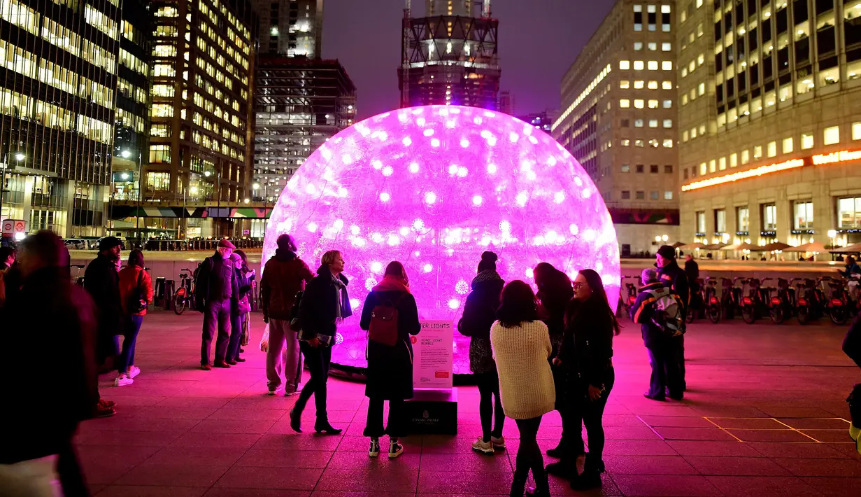 Sejumlah orang melihat seni instalasi lampu Sonic Light Bubble saat festival Canary Wharf Winter Lights di London (16/1). (Ian West / PA via AP)