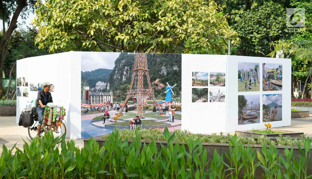 Pedagang bersepeda dekat foto yang dipajang dalam pameran bertajuk 'Identitas' pada acara Jakarta International Photo Festival (JIPFest) 2019 di Taman Menteng, Jakarta, Rabu (3/7/2019). JIPFest 2019 menghadirkan 50 fotografer internasional. (Liputan6.com/Immanuel Antonius)