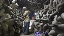 Perajin membuat patung Dewa Ganesha di sebuah bengkel di pinggiran Hyderabad, India, Rabu (18/8/2021). ​Patung ramah lingkungan yang dibuat jelang perayaan Ganesh Chaturthi tersebut dibuat dari lumpur, serat rami, dan bambu untuk mengurangi polusi air. (NOAH SEELAM/AFP)