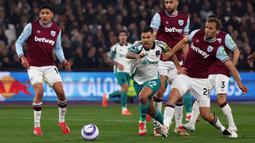 Pemain Newcastle, Bruno Guimaraes menggiring bola melewati sejumlah pemain West Ham dalam laga lanjutan Liga Inggris 2024/2025 di London Stadium, London, Inggris, Selasa (11/03/2025) dini hari WIB. (AFP/Adrian Dennis)