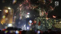Kembang api menghiasi malam pergantian tahun baru 2019 di kawasan Bundaran HI, Jakarta, Selasa (1/1). Hujan yang mengguyur Jakarta tidak menyurutkan warga menikmati kembang api tahun baru. (Liputan6.com/Angga Yuniar)