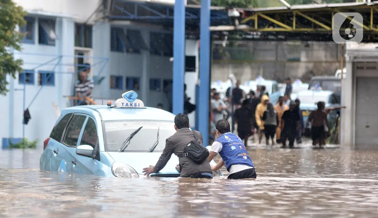 Sopir mendorong taksi untuk dipindahkan ke tempat lebih tinggi di Pool Blue Bird, Kramat Jati, Jakarta Timur, Rabu (1/1/2020). Banjir yang terjadi akibat hujan deras yang mengguyur Jakarta dan sekitarnya menyebabkan puluhan taksi dan belasan mobil terendam. (merdeka.com/Iqbal S. Nugroho)
