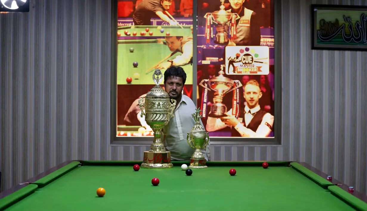 Mohammad Ikram, yang bermain snooker dengan dagunya, berpose untuk fotografer dengan piala di klub snooker lokal di kota Samundri, Pakistan, Minggu (25/10/2020). (AP Photo/Anjum Naveed)