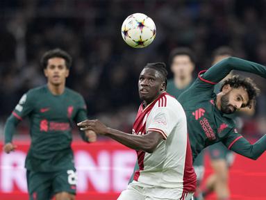 Bek Ajax Amsterdam Calvin Bassey berebut bola dengan penyerang Liverpool Mohamed Salah pada matchday kelima Grup A Liga Champions 2022-2023 di Johan Cruiff Arena,  Kamis (27/10/2022) dini hari WIB. Liverpool akhirnya ikut memastikan diri melaju ke babak 16 besar Liga Champions. (AP Photo/Peter Dejong)