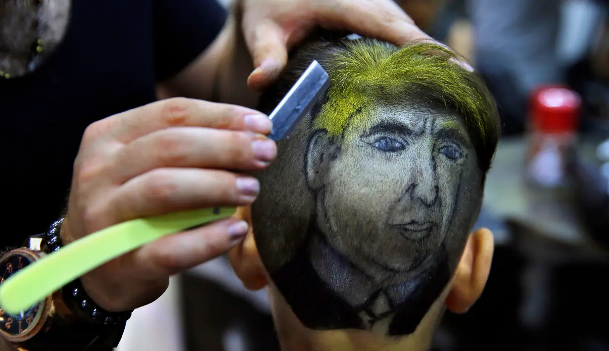 Muhannad Khaled Omar membuat lukisan bergambar Donald Trump dikepala pelanggannya di Burj al-Barajneh, Lebanon (14/7). Potongan rambut dengan bergaya lukisan ini menjadi tren di Lebanon.(AP Photo / Bilal Hussein)