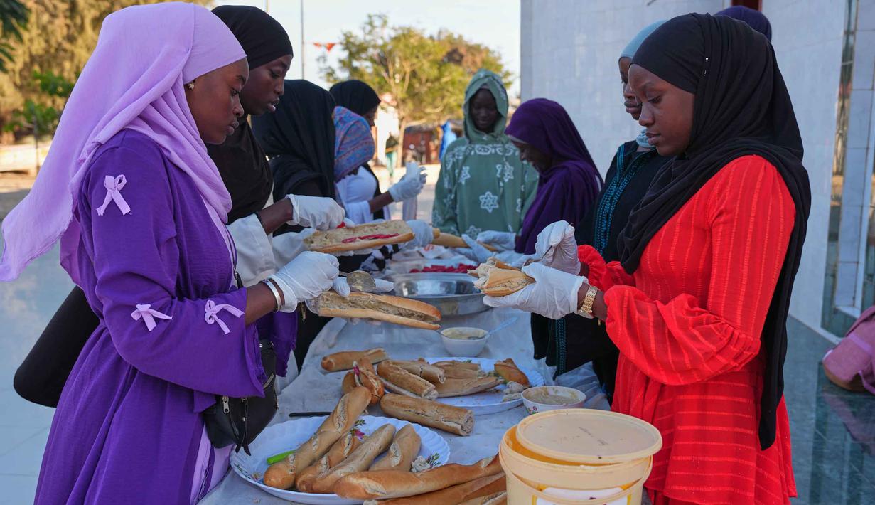 Menjelang waktu berbuka puasa, kelompok pemuda menyiapkan paket makanan ringan seperti roti isi sosis dan air. Tampak dalam foto, para wanita menyiapkan iftar, yaitu makanan berbuka puasa selama bulan suci Ramadan di Dakar, Senegal, Kamis, 5 Maret 2026. (AP Photo/Misper Apawu)
