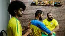 Helio Fonseca (kanan) dan Vinicius Alves (kiri) membantu teman mereka yang tuli dan buta Carlos Junior (tengah) dengan play-by-play pertandingan sepak bola Grup G Piala Dunia antara Brasil dan Swiss di Osasco, Sao Paulo, Brasil, 28 November 2022. Fonseca dan Alves menggunakan meja taktil dan sentuhan pada tubuh tunanetra dan tunarungu untuk menunjukkan kepada mereka pergerakan bola dan para pemain selama pertandingan sepak bola. (AP Photo/Marcelo Chello)