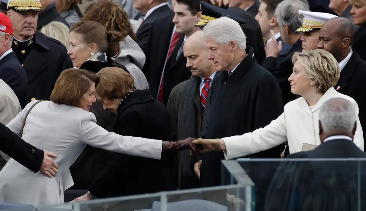 Mantan Menteri Luar Negeri AS, Hillary Clinton berjabat tangan dengan House Minority Leader, Nancy Pelosi usai upacara pelantikan Donald Trump menjadi Presiden AS ke-45 di Washington, DC, AS, (20/1). (Win McNamee/Pool Photo via AP)