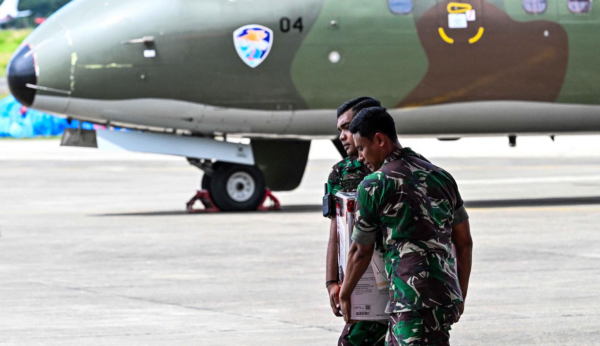 Untuk diketahui, Tentara Nasional Indonesia (TNI) mengerahkan 18 unit pesawat, termasuk Airbus A400M, Lockheed C-130 Hercules, Cassa NC212i, dan Cessna Caravan. Tampak dalam foto, personel TNI membawa generator sebelum mengantarkan bantuan kepada korban banjir di Pangkalan Tentara Nasional Indonesia (TNI) Angkatan Udara (AU) di Blang Bintang, Provinsi Aceh, pada Minggu 7 Desember 2025. (Chaideer MAHYUDDIN/AFP)