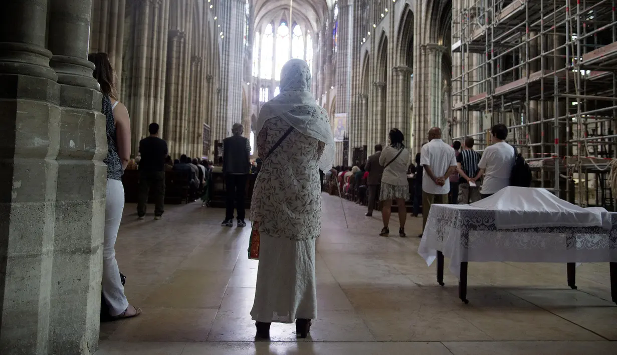 Seorang wanita muslim berdiri ketika menghadiri misa di Katedral Saint-Denis, dekat Prancis, Minggu (31/7). Muslim di penjuru Prancis menghadiri misa sebagai solidaritas atas pembunuhan seorang pastor oleh militan Islam. (Dominique Faget/AFP)
