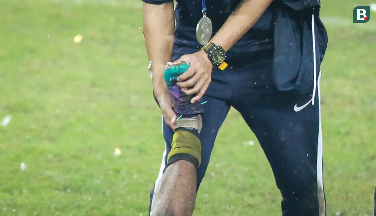 Pemain Timnas Malaysia U-19, Adam Farhan Mohd Faizal tengah mendapatkan perawatan dari salah satu official tim saat timnya merayakan juara Piala AFF U-19 2022 di Stadion Patriot Candrabhaga, Bekasi, Jumat (15/07/2022). (Bola.com/Bagaskara Lazuardi)
