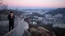 Pejalan kaki menikmati minuman sambil melihat kota Seoul saat matahari terbit di Korea Selatan (31/10). Seoul terletak di barat laut negara, di bagian selatan DMZ Korea, di Sungai Han. (AFP Photo/Ed Jones)