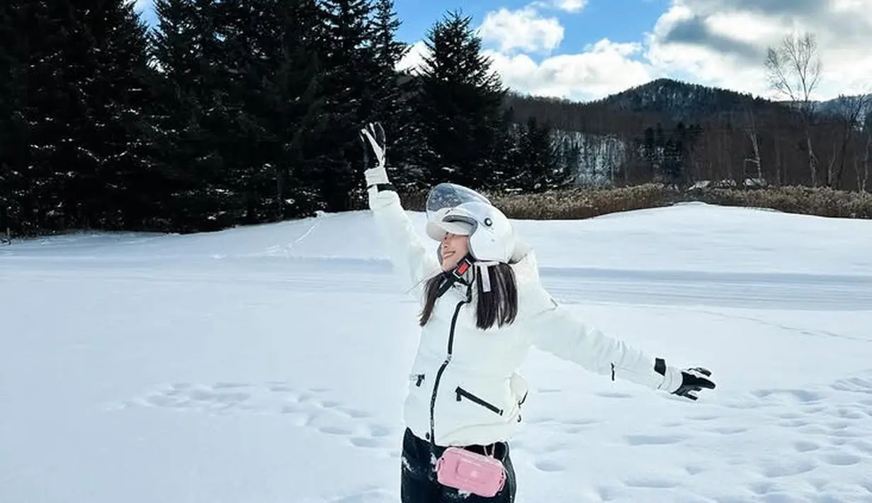 Ayu Dewi memilih menikmati salju di Jepang bersama keluarganya. Ia tampil dengan jaket putih dipadukan bawahan celana hitam sambil membawa tas Chanel pink. [@mrsayudewi]