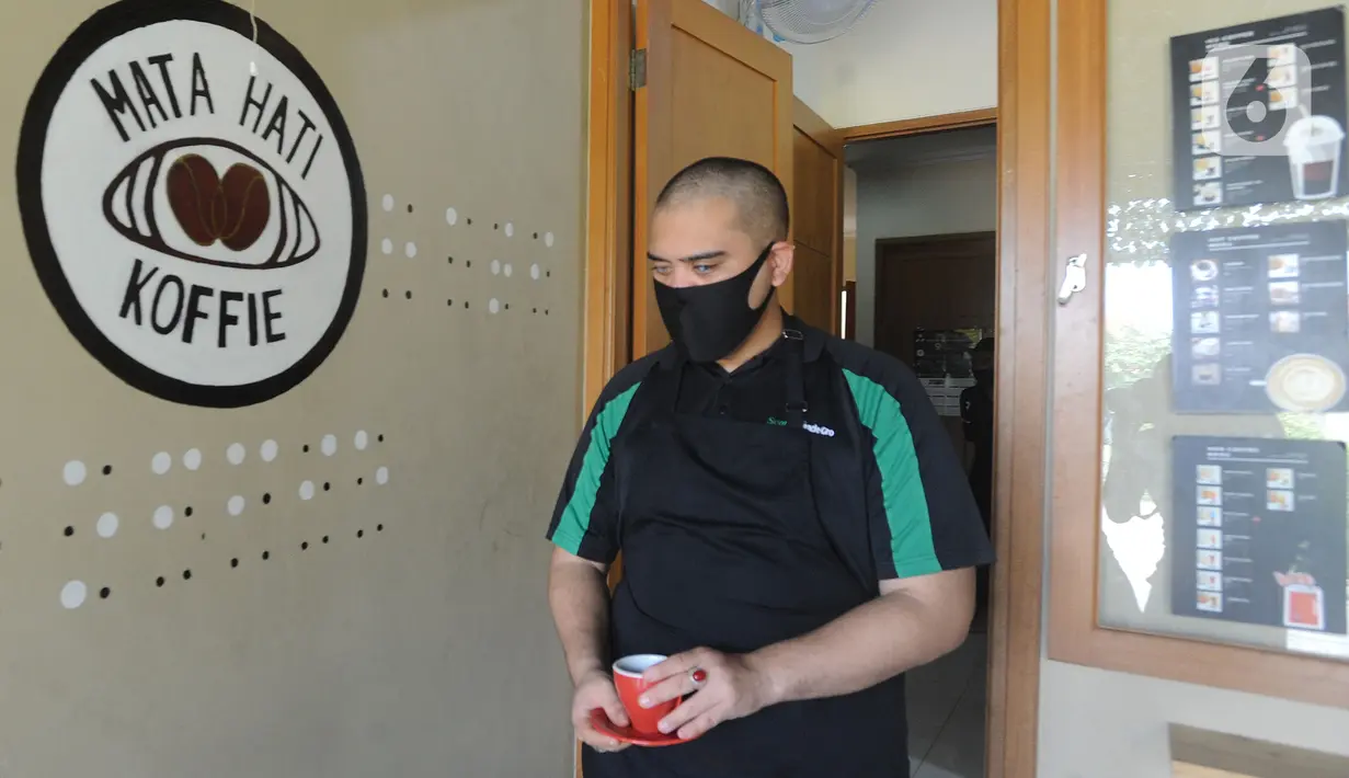 Ahmad Hilmy Almusawa, pemuda 22 tahun penyandang tunanetra membawa kopi untuk pelanggan di Mata Hati Koffie di Jalan Cabe, Pondok Cabe Ilir, Pamulang, Tangerang Selatan, Banten, Selasa (21/7/2020). (merdeka.com/Arie Basuki)