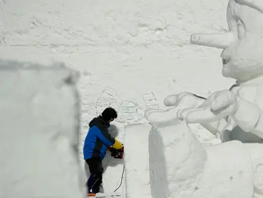 Seorang seniman mengukir patung es raksasa di Snow Land, PyeongChang, Korea Selatan, Minggu (4/2). Hal ini dilakukan untuk menyambut Olimpiade Musim Dingin PyeongChang 2018. (AP Photo/Charlie Riedel)