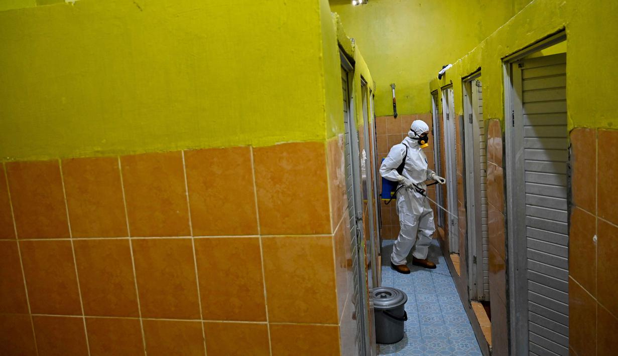 Seorang anggota Badan Penanggulangan Bencana Daerah (BPBD) menyemprotkan disinfektan di toilet sebuah Sekolah Menengah Pertama (SMP) dalam rangka program mitigasi pencegahan penyebaran flu burung di Banda Aceh pada Jumat 31 Oktober 2025. Sterilisasi difokuskan pada area asrama baik putri maupun putra. (Chaideer MAHYUDDIN/AFP)