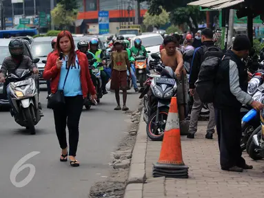 Warga melintas di samping trotoar yang dijadikan tempat parkir motor di Jalan Juanda, Bekasi, 4 Oktober 2016. Trotoar yang seharusnya untuk pejalan kaki ini dialih fungsikan oleh jasa parkir liar sebagai tempat parkir kendaraan bermotor. (Foto: Fajar)