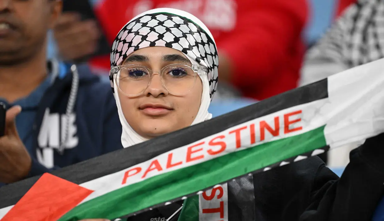 Seorang pendukung memegang syal sebelum dimulainya pertandingan sepak bola Grup C Piala Asia AFC Qatar 2023 antara Palestina dan Uni Emirat Arab di Stadion Al-Janoub di Al-Wakrah, Doha pada 18 Januari 2024. (HECTOR RETAMAL/AFP)