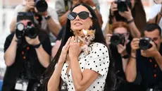 Aktris AS Demi Moore berpose dengan anjing Chihuahua miliknya bernama Pilaf pada sesi pemotretan untuk film "The Substance" di Festival Film Cannes ke-77, Prancis selatan, Senin (20/5/2024). (CHRISTOPHE SIMON / AFP)