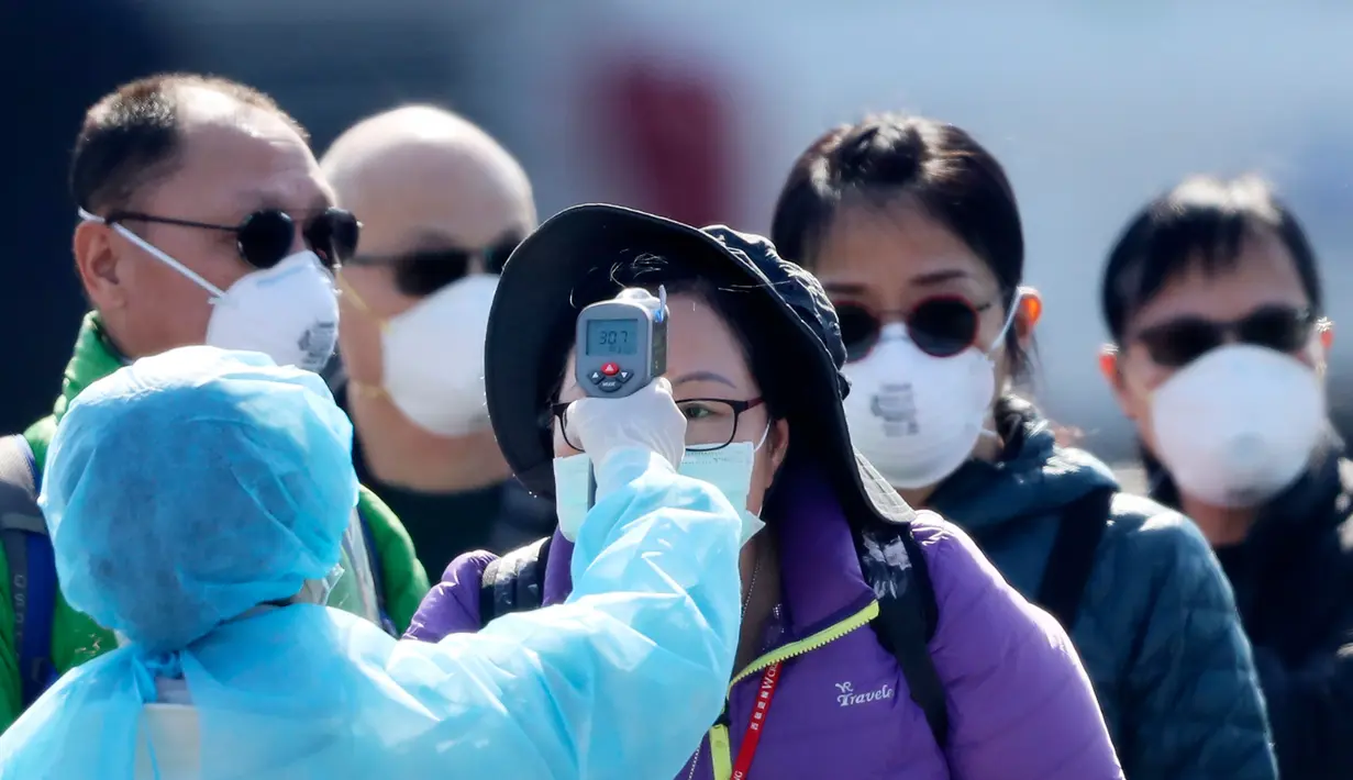 Petugas memeriksa suhu tubuh penumpang asing yang turun dari kapal pesiar Diamond Princess yang dikarantina di Yokohama, Jepang, Jumat (21/2/2020). Sebanyak 74 WNI berada dalam kapal pesiar Diamond Princess, empat di antaranya positif terjangkit virus corona (COVID-19). (AP Photo/Eugene Hoshiko)