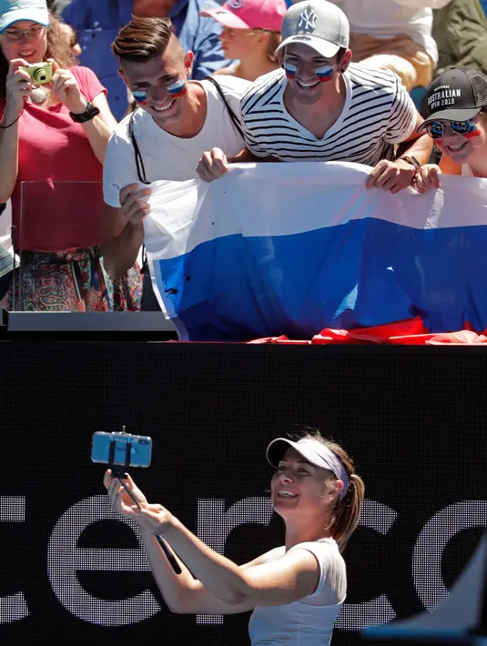 Ekspresi Maria Sharapova saat berselfie dengan penggemarnya usai pertandingan melawan Tatjana Maria pada putaran pertama di kejuaraan tenis Australia Terbuka 2018 di Melbourne (16/1). Sharapova menang 6-1, 6-4. (AP Photo / Vincent Thian)