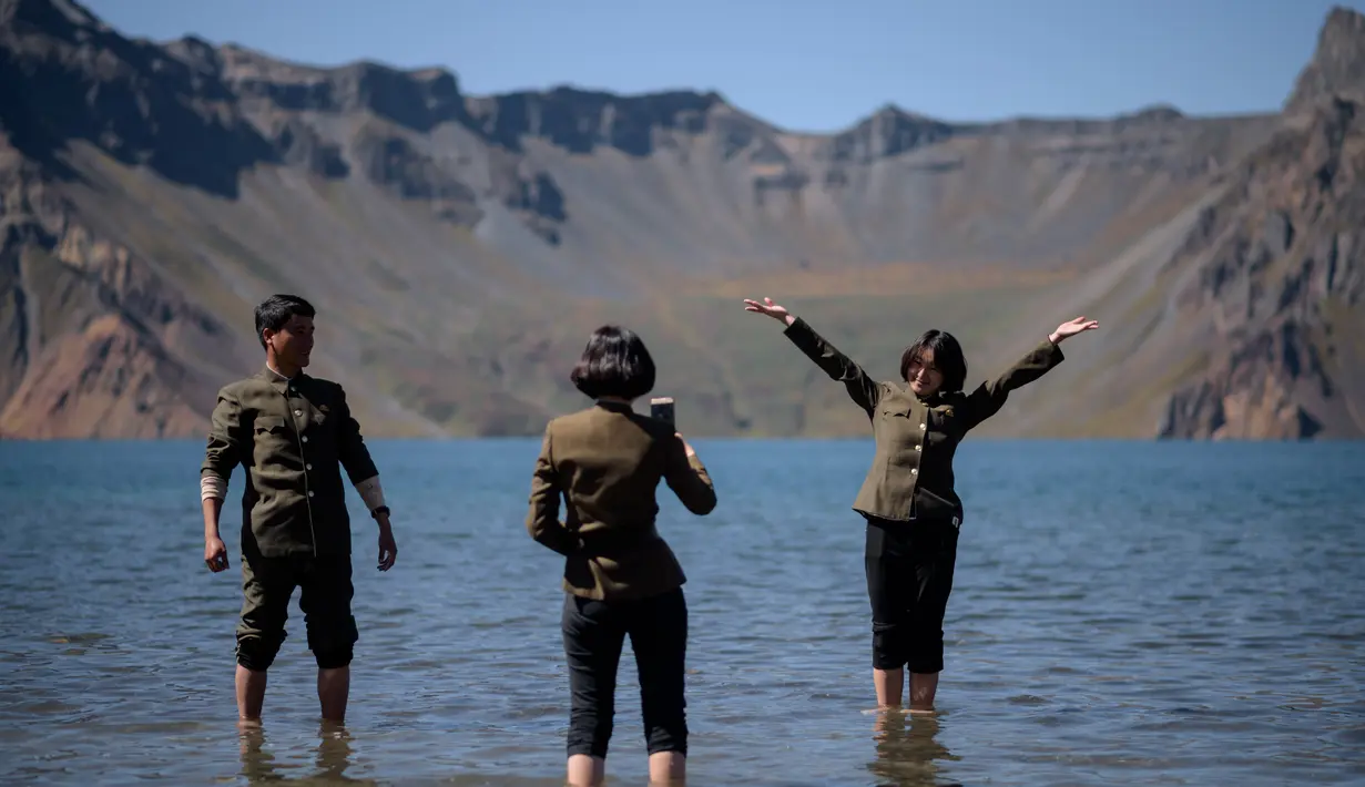 Gambar pada 11 September 2019, siswa Korea Utara berpose di danau Chonji atau 'Heaven lake' saat mengunjungi kawasan Gunung Paektu di Samjiyon. Banyak wisatawan yang datang untuk bersantai di pinggiran danau dan berfoto dengan latar belakang danau surga itu. (Photo by Ed JONES / AFP)