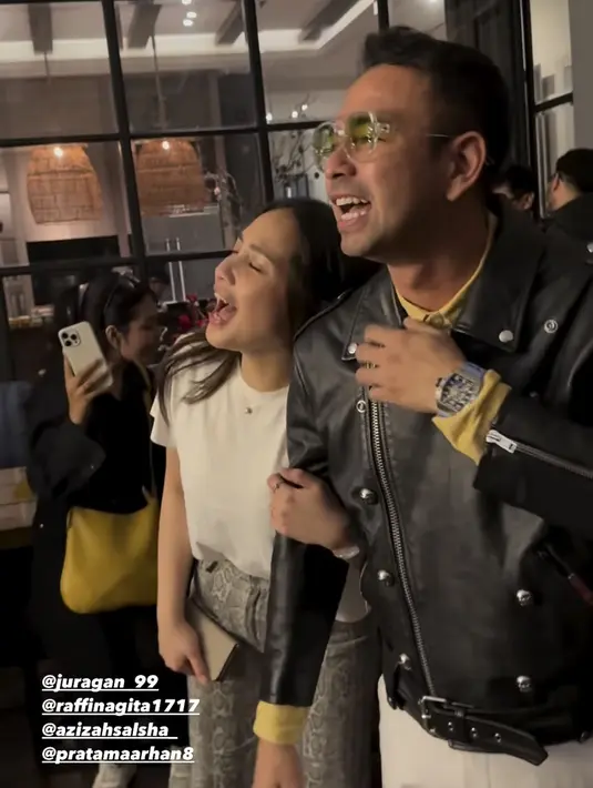 Nagita Slavina mengenakan t shirt putih dipadukan celana panjang motif ular abu-abu. Raffi mengenakan jaket kulit hitam.  [@shandypurnamasari]