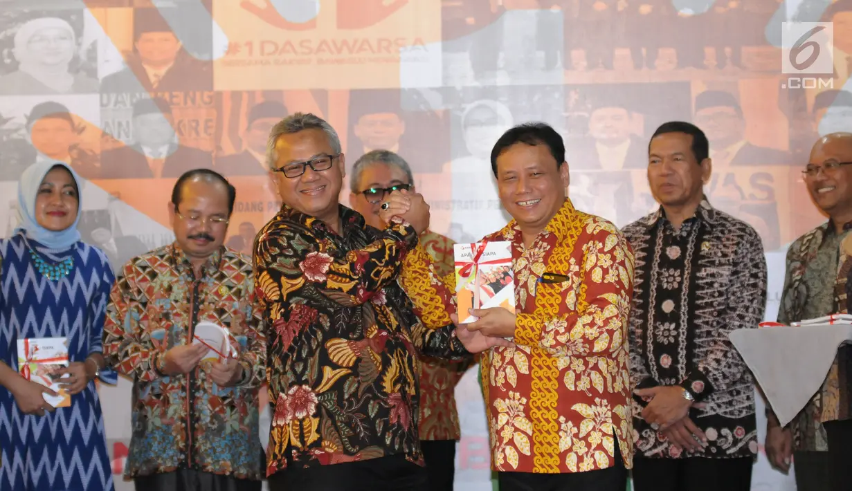 Ketua Bawaslu, Abhan (kanan depan) menyerahkan buku perjalanan Bawaslu kepada Ketua KPU RI, Arief Budiman pada perayaan HUT 1 Dasawarsa Bawaslu di Jakarta, Senin (9/4). (Liputan6.com/Helmi Fithriansyah)