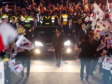 Ratusan pendukung mengibarkan bendera nasional menyambut mantan Presiden Korsel, Park Geun-hye di rumah pribadinya di Seoul, Minggu (12/3). Park Geun-hye meninggalkan Blue House setelah resmi dimakzulkan Mahkamah Konstitusi (MK) Korsel. (str/YONHAP/AFP)