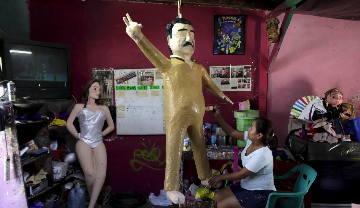 Pekerja saat mengecat boneka raja narkoba Joaquin "El Chapo" Guzman saat menyelesaikannya di Reynosa, Meksiko (21/7/2015). Guzman melarikan diri dari penjara melalui terowongan yang ia buat pada bulan lalu. (REUTERS/Daniel Becerril)