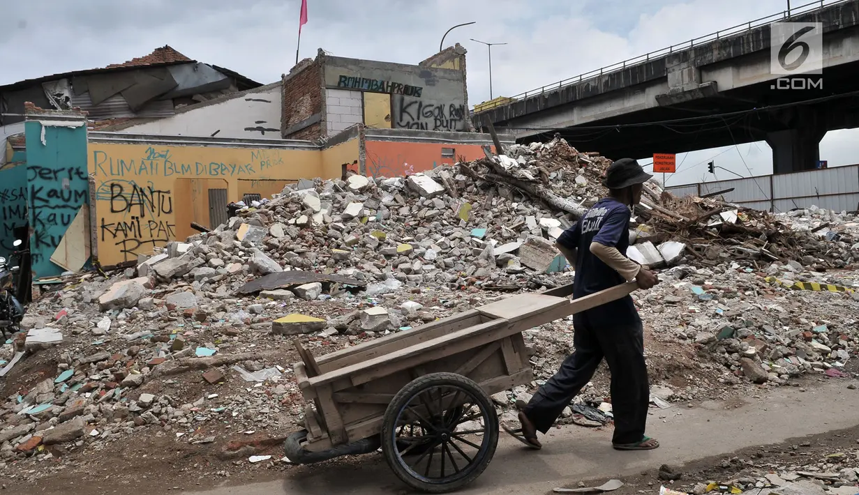 Warga melintasi bangunan permukiman yang belum dibongkar di kawasan Rawa Bunga, Jakarta, Rabu (13/3). Pembongkaran bangunan dilakukan untuk lahan pembangunan Tol Becakayu seksi 1a rute Casablanca-Cipinang Melayu. (merdeka.com/Iqbal S. Nugroho)
