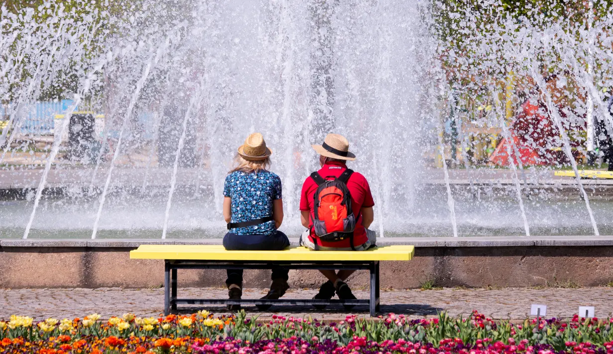 Pengunjung bersantai di depan air mancur di pameran hortikultura EGA (Erfurt Garden Construction Exhibition) di Erfurt, Jerman, Kamis (19/4). Masyarakat Jerman banyak memilih bersantai di taman saat musim semi. (AP Photo/Jens Meyer)