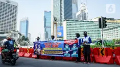 Petugas kepolisian membentangkan spanduk saat sosialisasi pelaksanaan ganjil genap di Kawasan Bundaran HI, Jakarta, Minggu (2/8/2020). Ditlantas Polda Metro Jaya kembali memberlakukan sistem ganjil genap di 25 ruas jalan protokol  DKI Jakarta mulai Senin, 3 Agustus 2020. (Liputan6.com/Faizal Fanani)