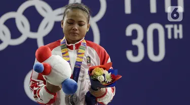 Lifter putri Indonesia, Lisa Setiawati saat naik podium usai mendapatkan medali perak SEA Games 2019 cabang angkat besi nomor 45 kg di Stadion Rizal Memorial, Manila, Minggu (1/12/2019). Dirinya meraih perak dengan total angkatan 169 kg. (Bola.com/M Iqbal Ichsan)