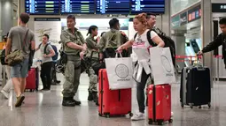 Penumpang melintas saat polisi anti huru-hara berjaga di stasiun Airport Express di Central yang menghubungkan ke Bandara Internasional Chek Lap Kok, Hong Kong (7/9/2019). Pengunjuk rasa pro-demokrasi berencana mengganggu jaringan transportasi ke bandara pada 7 September. (AFP Photo/Anthony Wallace)