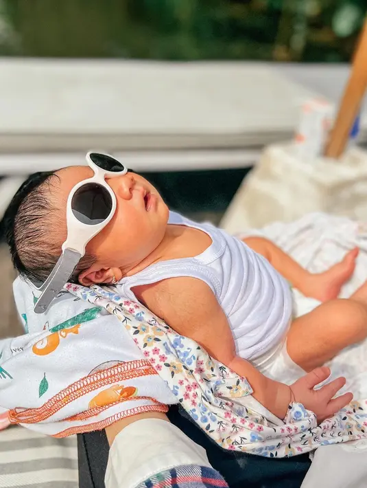 Baby Ara saat berjemur. Dia megenakan kacamata yang kebesaran untuk menghalau sinar matahari langsung. (Foto: Instagram/ _irishbella_)